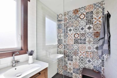 Small white walk-in shower, multi-colored pattern wall