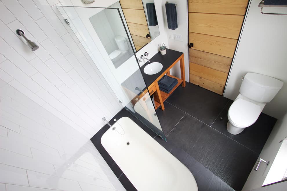 Modern bathroom, white tile walls, grey slate tile floor, wooden open cabinets