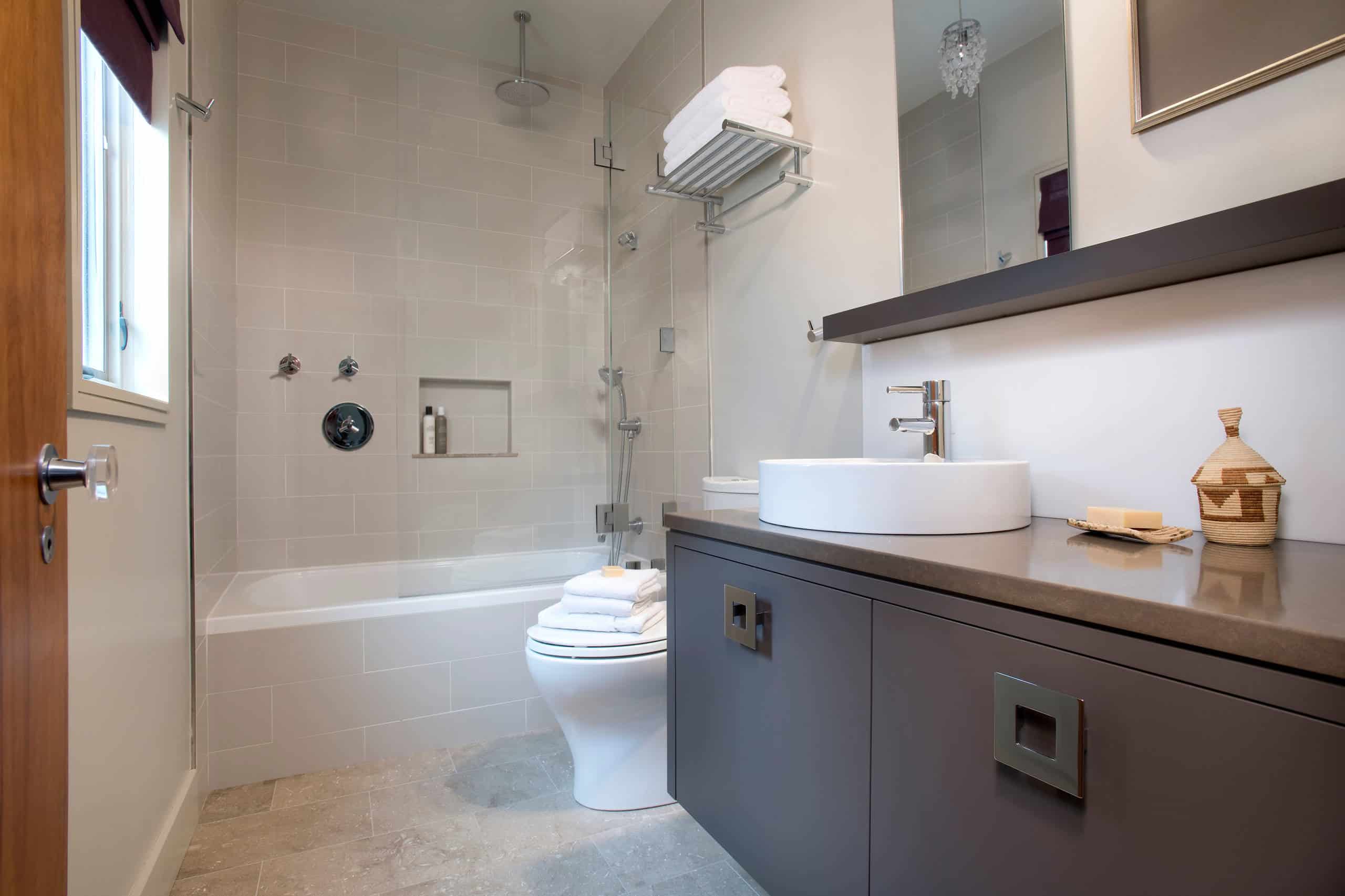 Minimalist bathroom, grey tile walls, grey limestone tile floor, brown cabinets