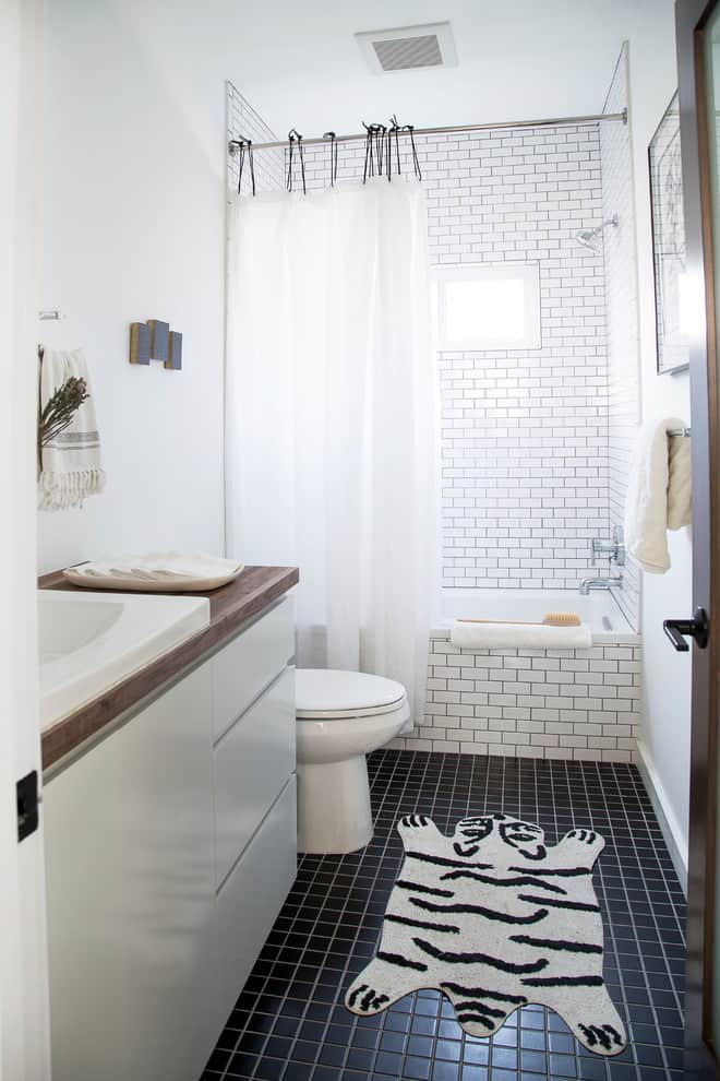 Black tile floor, white tile walls, white cabinets