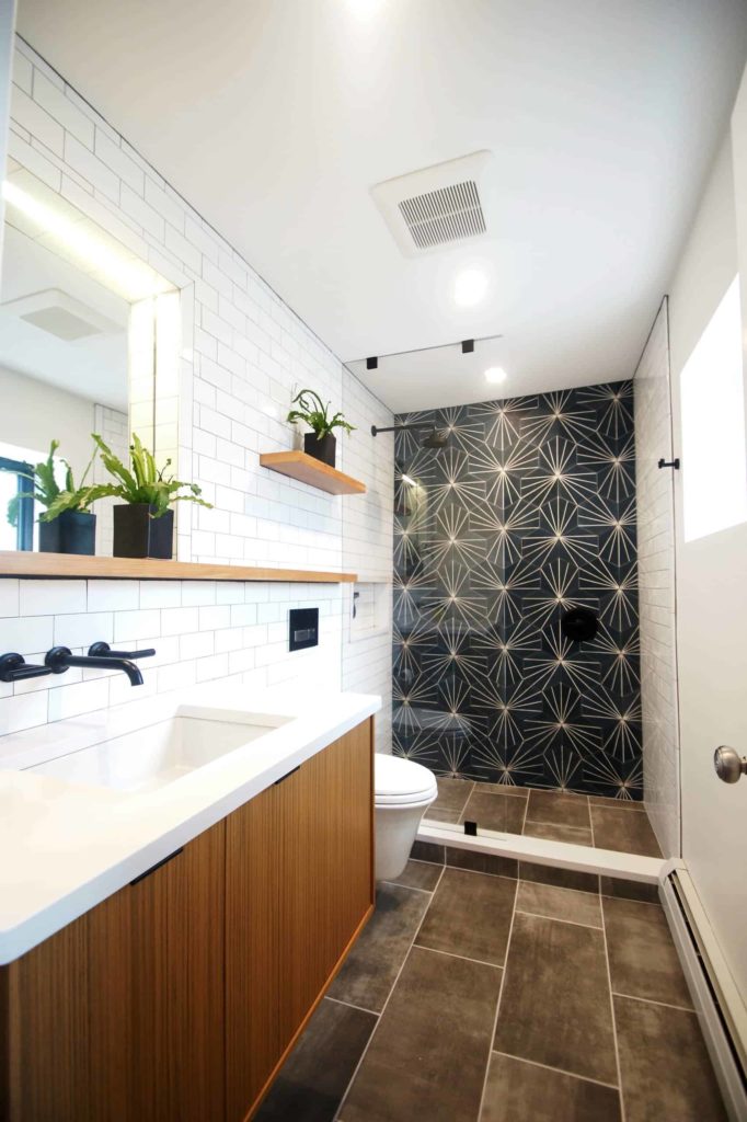 Brown tile floor, white tile walls, one wall is black pattern one