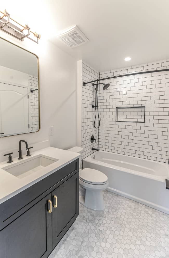 Grey honey comb marble tile floor, white tile walls, black cabinets