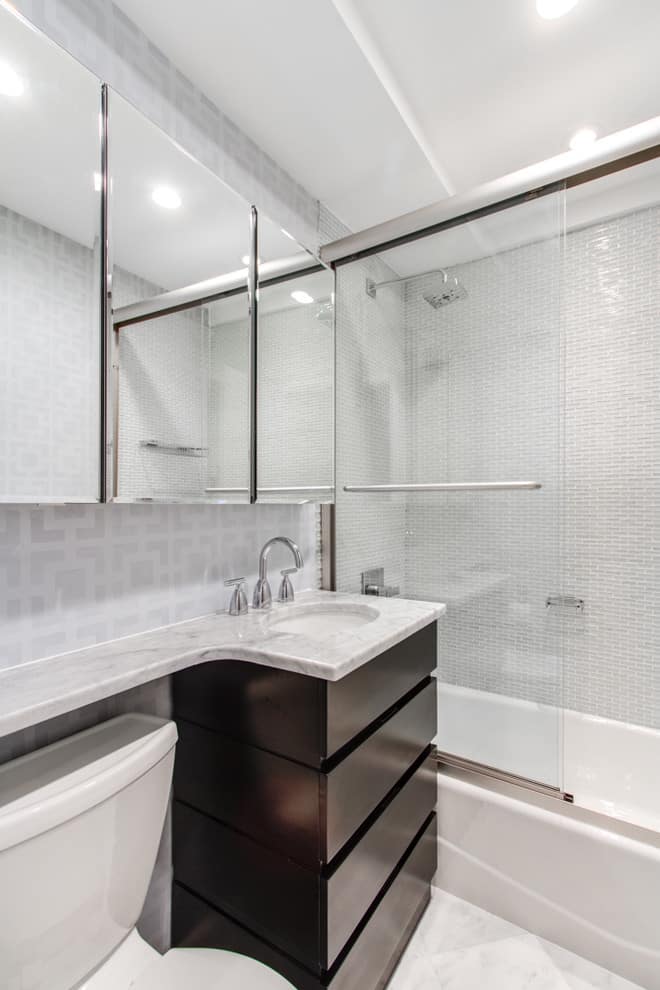 Grey tile walls, marble tile floor, dark wood cabinets