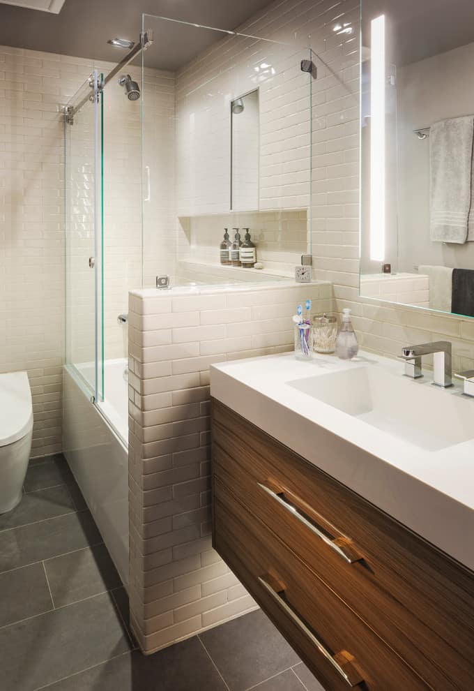 Dark grey tile floor, white tile walls, wooden cabinets