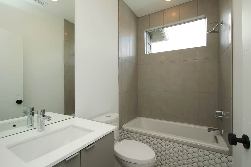 White honey comb tile bathtub, grey cabinets, grey tile walls