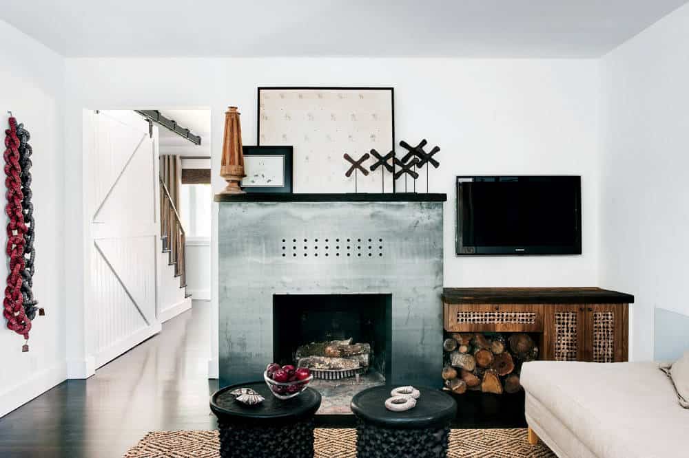 Small living room with wooden floor, brown patterned rug, white walls and a sofa, grey stone fireplace-hearth and a TV next to the fireplace