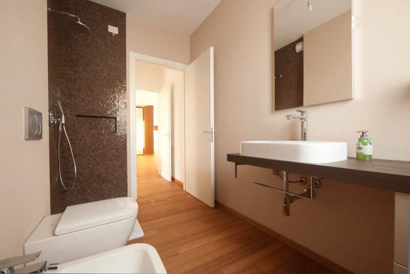 Example of a mid-sized minimalist master brown tile and mosaic tile bamboo floor corner shower design in Milan with a console sink, wood countertops, a two-piece toilet and beige walls