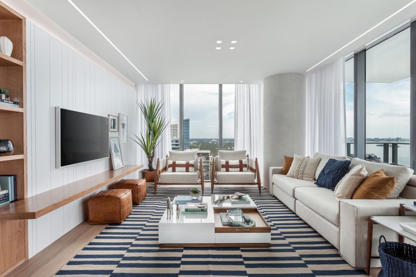 Family room - large coastal open concept light wood floor family room idea in Miami with white walls, a wall-mounted tv and no fireplace